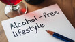© Lisa - Alcohol-free lifestyle goals written on notepad, with red wine glass in background, promoting a sober lifestyle