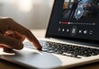 © Syam - Person using a laptop computer to watch a video online. Finger pressing a key to pause the streaming media player for digital entertainment
