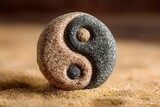 Close-up of a yin-yang symbol carved into a stone, resting on sand