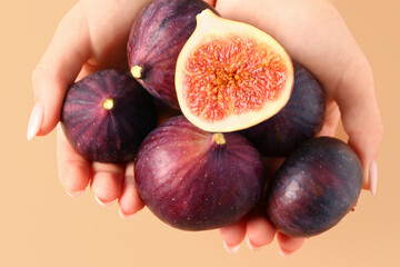 Wall Mural - female hands with slices of ripe fresh figs on orange background