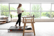 © Pixel-Shot - Young businesswoman with notebook training on treadmill at table in office