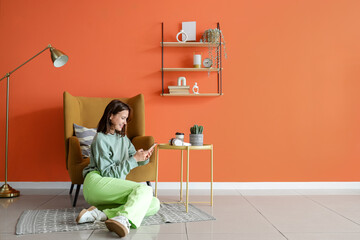 Poster - young woman using mobile phone near armchair at home