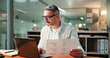 © peopleimages.com - Mature, businessman and night with documents on laptop for performance review or analysis in office. Man, financial advisor or working late with paperwork, statistics or report deadline in workplace