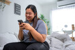© Kawee - Asian young plus-size woman using smartphone in cozy room at home.