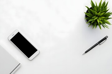 top view of minimalist white desk with smartphone, pen, and single green plant 
