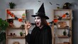 © kinomaster - A vampire witch in a black cloak and hat makes an OK gesture with her fingers