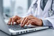 © Fahri - Doctor's hands typing on a laptop. Close-up view of a person in a white coat, focused on a computer keyboard