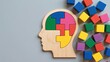 © Sohail - Mind Puzzle: Wooden silhouette of a head, filled with colorful puzzle pieces representing the intricate workings of the human mind and scattered building blocks around.