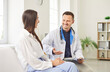 © Studio Romantic - Smiling male doctor or nurse conducts a medical consultation for a female patient in a hospital office. The healthcare visit focuses on providing physician care and patient support.