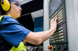 © Westend61 - Maintenance engineer in protective workwear operating CNC machine keypad in modern factory