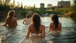 © sommersby - Back view of women enjoying peaceful, sun-drenched swim in serene river at golden hour, surrounded by lush nature with distant urban buildings