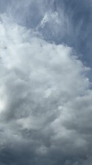 Wall Mural - Cumulus clouds change in atmospheric space under the action of wind. Natural blue sky background. Scenic cloudscape. Weather forecast. Accelerated vertical video, timelapse