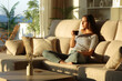 © PheelingsMedia - Relaxed woman on a sofa drinking cofee looking away