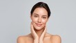© 69 - Natural beauty portrait of a smiling young woman with flawless skin, touching her face gently against a soft gray background