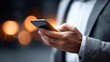 © Inrow Studio - A businessman in a suit using a smartphone, possibly for work or networking.