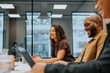 © Johnér - Smiling female entrepreneur sitting with colleagues in meeting room at office