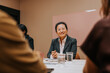 © Johnér - Smiling mature female business entrepreneur sitting at table in board room at office