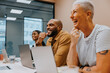 © Johnér - Smiling male entrepreneur sitting with female colleagues in meeting room at office