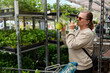 © Johnér - Woman sniffing plant leaves while shopping at plant nursery