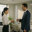 © j_everton - Two colleagues exchange a business card in a professional office setting, symbolizing a meeting, networking, or business dealings. The scene conveys politeness and respect.