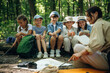 © standret - Survival tips, sitting at camp. Woman is doing tour for group of kids in the forest