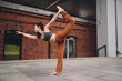 © BullRun - Athletic woman practicing yoga dancer pose on city pavement, extending arm forward with grace. Conceptual photo symbolizing empowerment, focus, resilience, balance, and mindfulness in modern life.