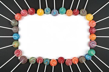 Wall Mural - colorful lollipops arranged with empty white area for children on a dark backdrop