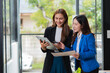 © maeching - Asian businesswoman using digital laptop while standing in front of modern building. Attractive female employee working in front of office.