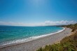 Wide-angle shot of a vast pebble shoreline along a scenic coastal region. Premium resolution image.