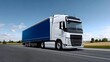 © pkproject - A large semi-truck with a blue trailer is speeding down a highway, surrounded by a countryside landscape of fields and blue sky with fluffy white clouds.