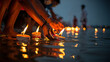 © Tamal - Hands gently placing small, lit oil lamps (diyas) onto the surface of the water at dusk, creating a beautiful and sacred festival of lights.