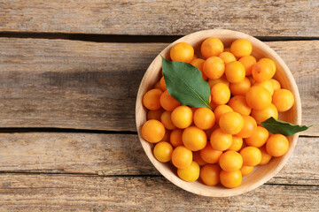Wall Mural - Ripe yellow cherry plums and leaves on wooden table, top view. Space for text