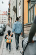 © Maskot - Rear view of mother holding hands of son while walking on sidewalk