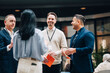 © Maskot - Smiling male business professionals talking with female colleague at networking event in convention center