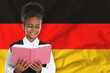 © New Africa - Little girl with book against flag of Germany. Language school