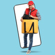 © New Africa - Food delivery service worker with thermo bag walking out of mobile phone display against light blue background. Online order