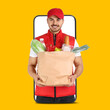 © New Africa - Delivery service worker giving online order out of mobile phone against orange background. Man with paper bag full of food products