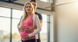 © Vasiliy - Pregnant blonde woman with partner in pink top at modern gym. Fitness couple maternity moment for prenatal exercise and wellness program documentation