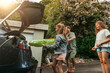 © Maskot - Daughter helping father loading pool raft in car trunk for summer holiday at driveway