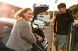 © Maskot - Smiling woman refueling electric car at charging station on street