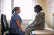 © Maskot - Side view of female medical expert talking with teenage girl sitting on examination table in hospital