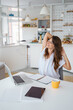 © Dorde - Relaxed Young Woman Stretching At Desk During Remote Work Break In Sunlit Modern Kitchen Space