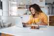 © Dorde - Bright Home Office with Stylish Decor Featuring a Woman Using Technology and Enjoying a Warm Beverage