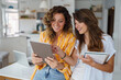 © Dorde - Smiling Women Working Together on a Tablet in a Stylish Bright Apartment Home Office