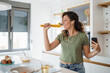 © Dorde - Young Woman Singing and Dancing Joyfully in a Bright Modern Kitchen Holding Phone and Pasta