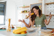 © Dorde - Two Happy Women Cooking and Singing Together in a Brightly Lit Modern Kitchen Space