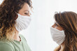© Dorde - Two Caucasian Female Friends Smiling While Wearing Face Masks in Bright Natural Lighting