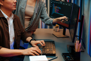 IT developers discussing with point to intelligent website development coder system running data online two screens information technology at neon light room at modern office. Infobahn.