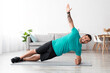 © Prostock-studio - Happy young muscular caucasian man athlete in uniform doing side plank on floor in living room interior. Sport at home, workout and new normal, fitness and exercises, active lifestyle, empty space