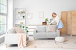 © Pixel-Shot - Female interior designer adjusting cushion on sofa in living room